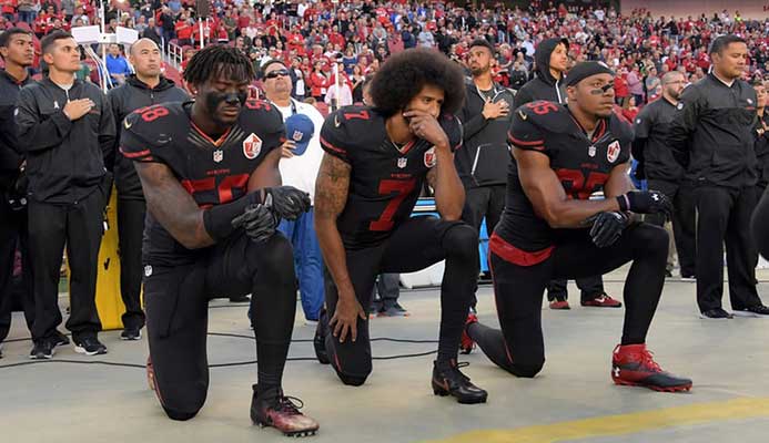 Colin Kaepernick, center, protests before a game against the Arizona Cardinals last October. Photograph: USA Today Sports