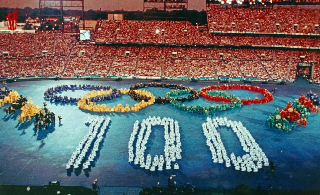 Call to Nations, the first segment of the 1996 Atlanta Olympic games opening ceremony, designed by Peter Minshall. The performers formed the Olympic rings and the number 100 to represent 100 years since the founding of the modern Olympics in 1896. Photo courtesy Don Mischer, producer of the ceremonies. -