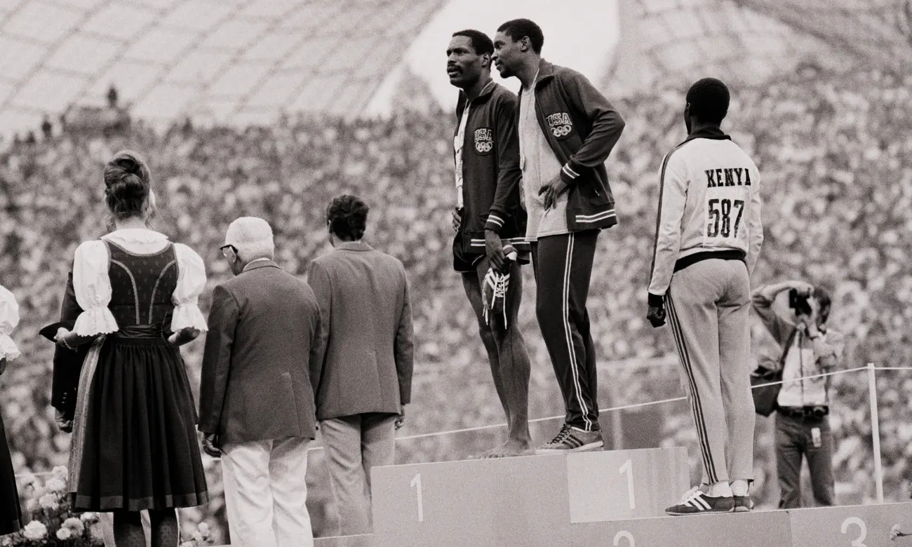 Vincent Matthews (hand on hip) and Wayne Collett (barefoot, holding shoes) chat during the 400m medal ceremony at the 1972 Olympics. Photograph: Bettmann/Bettmann Archive (image via: theguardian.com)